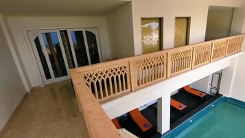 A pool area with a wooden railing, a door with glass panels, and a view of a building outside.
