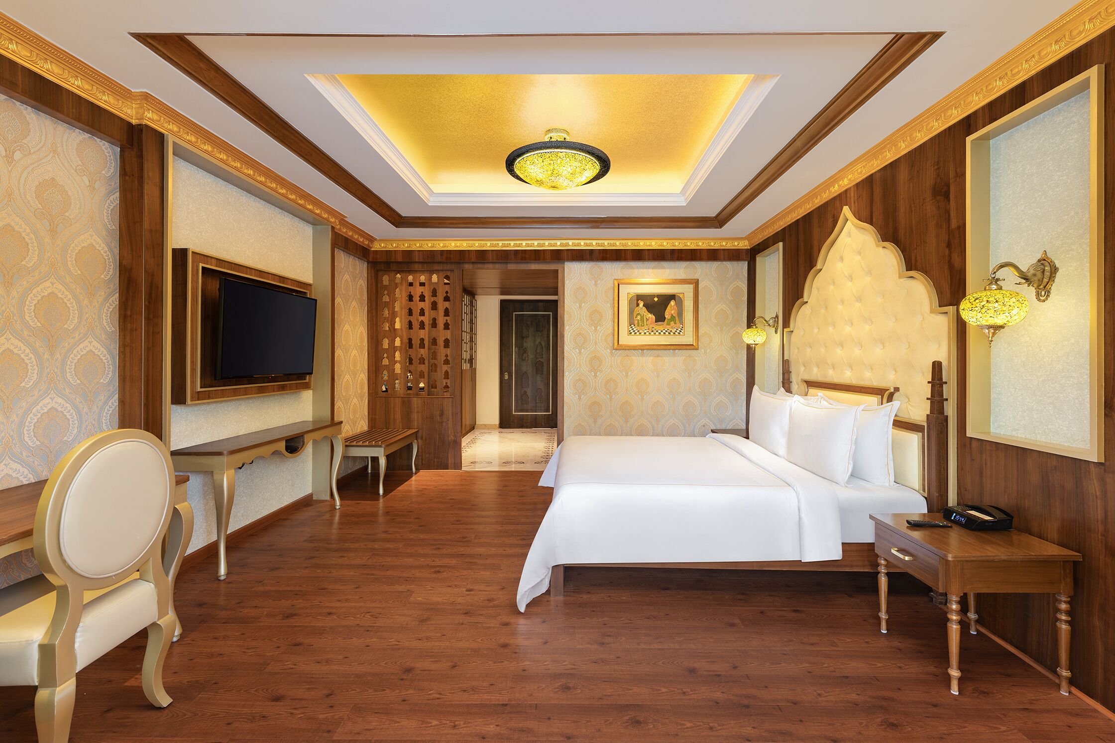 A hotel room with a large bed, a TV, a desk, and a chair.