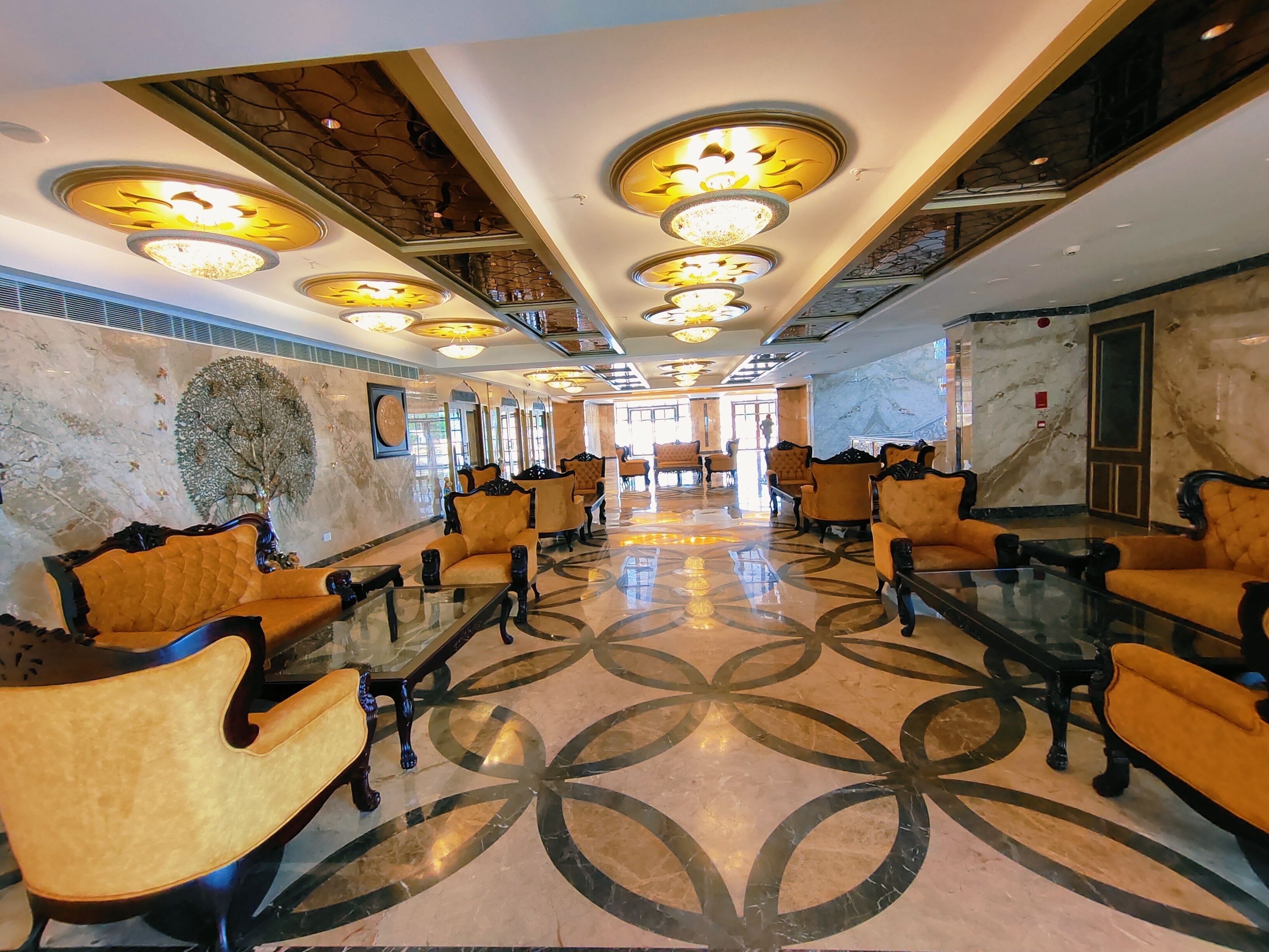 A spacious lobby with a marble floor, multiple seating areas, and decorative ceiling lights.