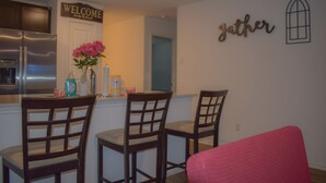 A kitchen with a stainless steel refrigerator, a welcome sign, and a 'gather' sign on the wall. - Dreamville (Maxwell)