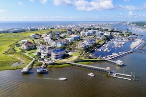 Luchtbeeld van een kustplaatsje met woongebouwen, een jachthaven en een brug naar het vasteland.
