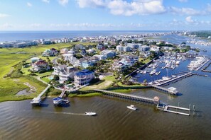 An aerial view of a coastal town with a marina, residential buildings, and a large house with a dock.
