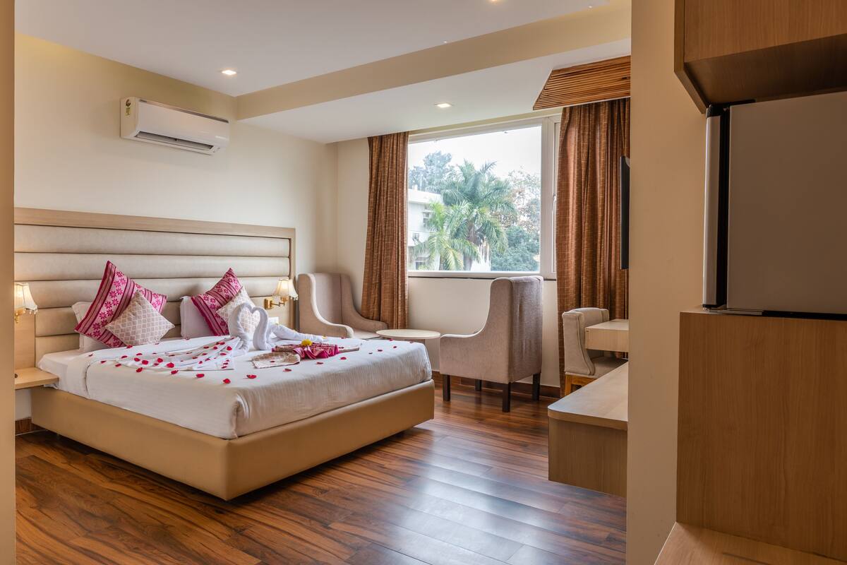A hotel room with a large bed, a desk, a chair, and a TV.