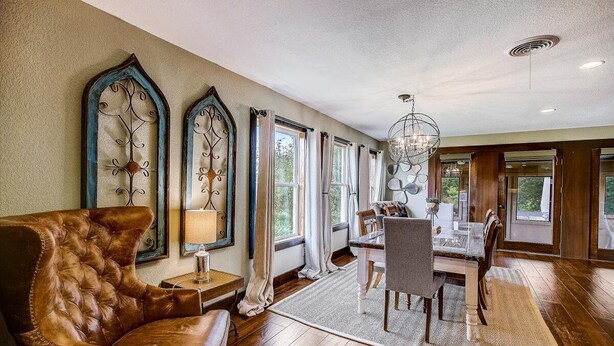 A spacious room with a large leather armchair, a dining table with chairs, and a chandelier. - Sandy Feet Retreat on LBJ - Pool, Hot Tub, Kayaks (Kingsland)