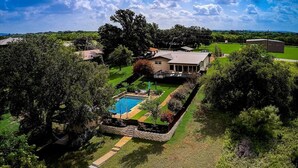 A residential property with a swimming pool, a large house, and surrounding greenery. - Sandy Feet Retreat on LBJ - Pool, Hot Tub, Kayaks (Kingsland)