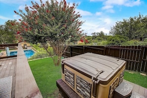 A backyard with a hot tub, a wooden deck, a swimming pool, and a tree with red flowers. - Sandy Feet Retreat on LBJ - Pool, Hot Tub, Kayaks (Kingsland)