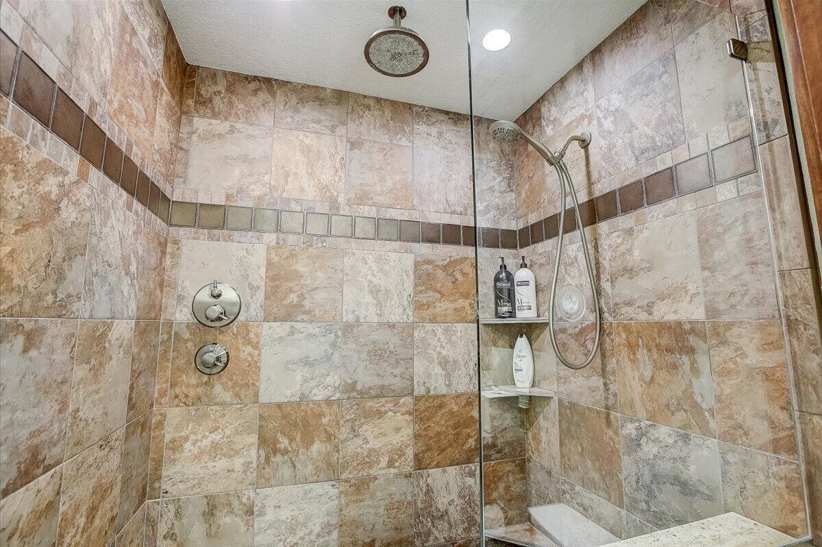 A bathroom with a shower, a toilet, and a shelf with toiletries.