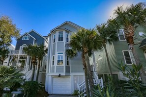 A row of coastal-style houses with a central building featuring a garage and a small porch. - Ocean Views, Two Master Suites, Screened Porch & Access to Ocean Point Community Pool & Cabana (Isle of Palms)