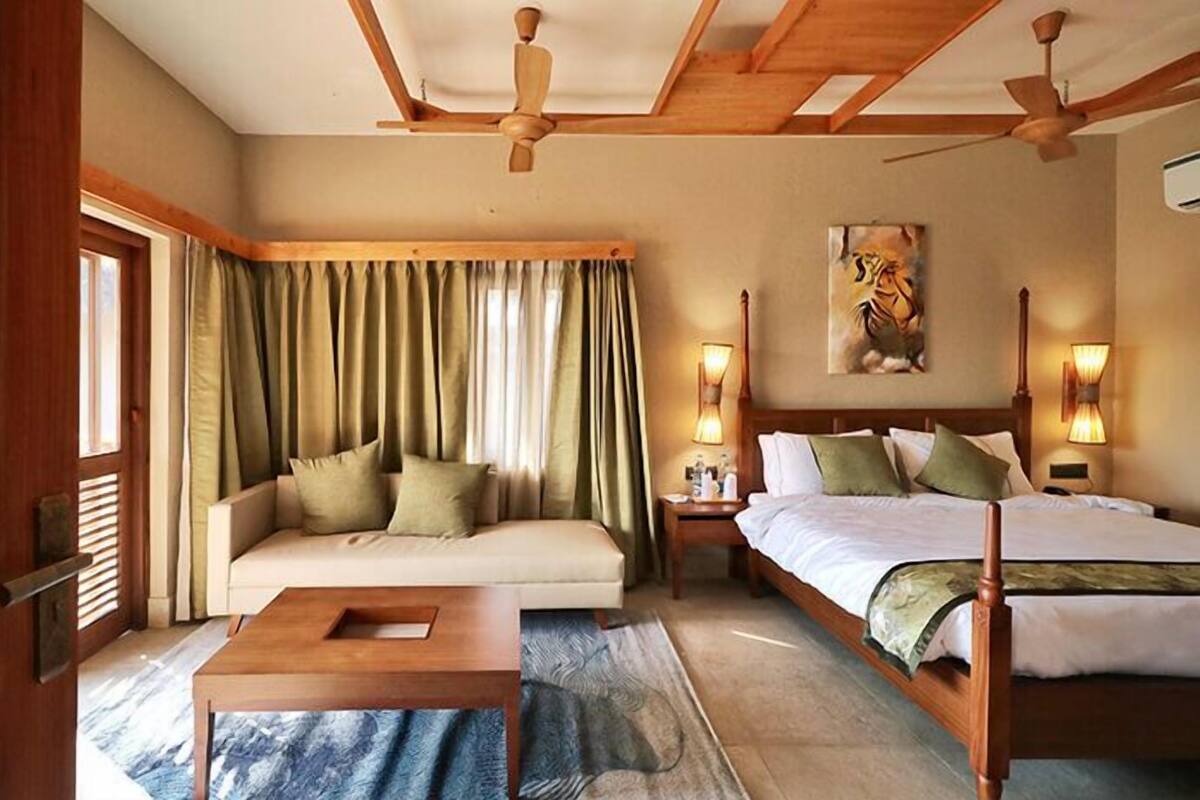 A bedroom with a wooden ceiling, a bed, a sofa, a nightstand, and a painting on the wall.