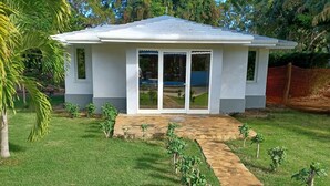 Una piccola casa a un piano con tetto piano e portico coperto.