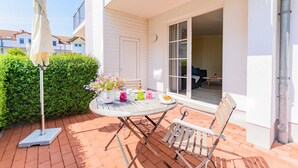 An outdoor patio with a round table, chairs, a potted plant, and a white umbrella. - House B - Whg 01 with terrace - F: Lotsenberg Apartments with 8 apartments (Mönchgut)