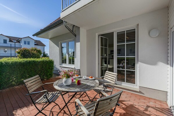 A patio with a round table, chairs, and a potted plant.