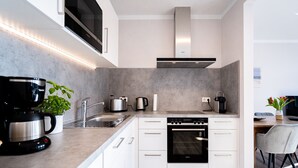 Eine moderne Küche mit weißen Schränken, einem eingebauten Backofen, einer Mikrowelle und einer Kaffeemaschine.