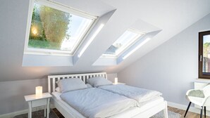 Ein modernes Schlafzimmer mit Dachfenster, einem Bett, Nachttischen und einem Schreibtisch mit Stuhl.