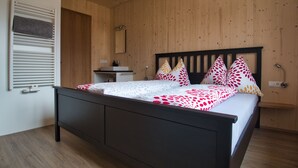 Une chambre avec un plafond en bois, un lit avec une literie à motifs, une table de chevet et un miroir.
