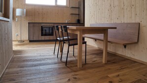 Une cuisine moderne avec des meubles en bois, un four encastré et un coin repas comprenant une table et des chaises.