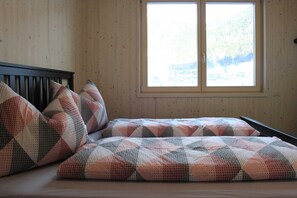 A bedroom with a bed, a window, and wooden walls.