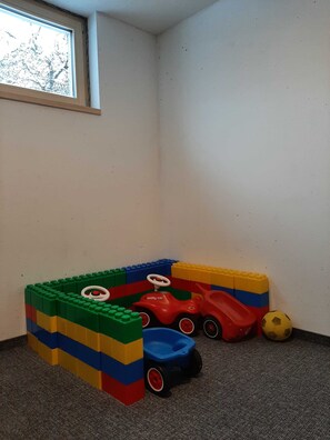 Een hoekzaal met een raam, een kleurrijk speelgedeelte en een vloerbedekking.