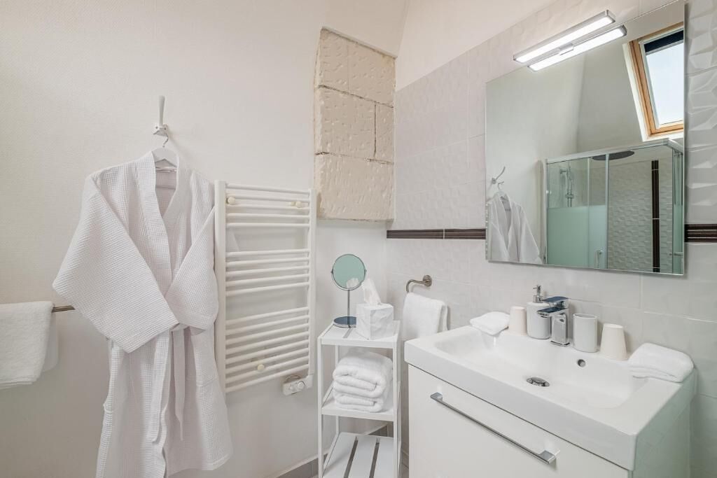A modern bathroom with a white sink, mirror, and towel rack.
