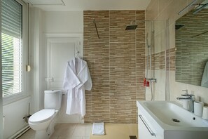 Uma casa de banho moderna com chuveiro, sanita e lavatório.