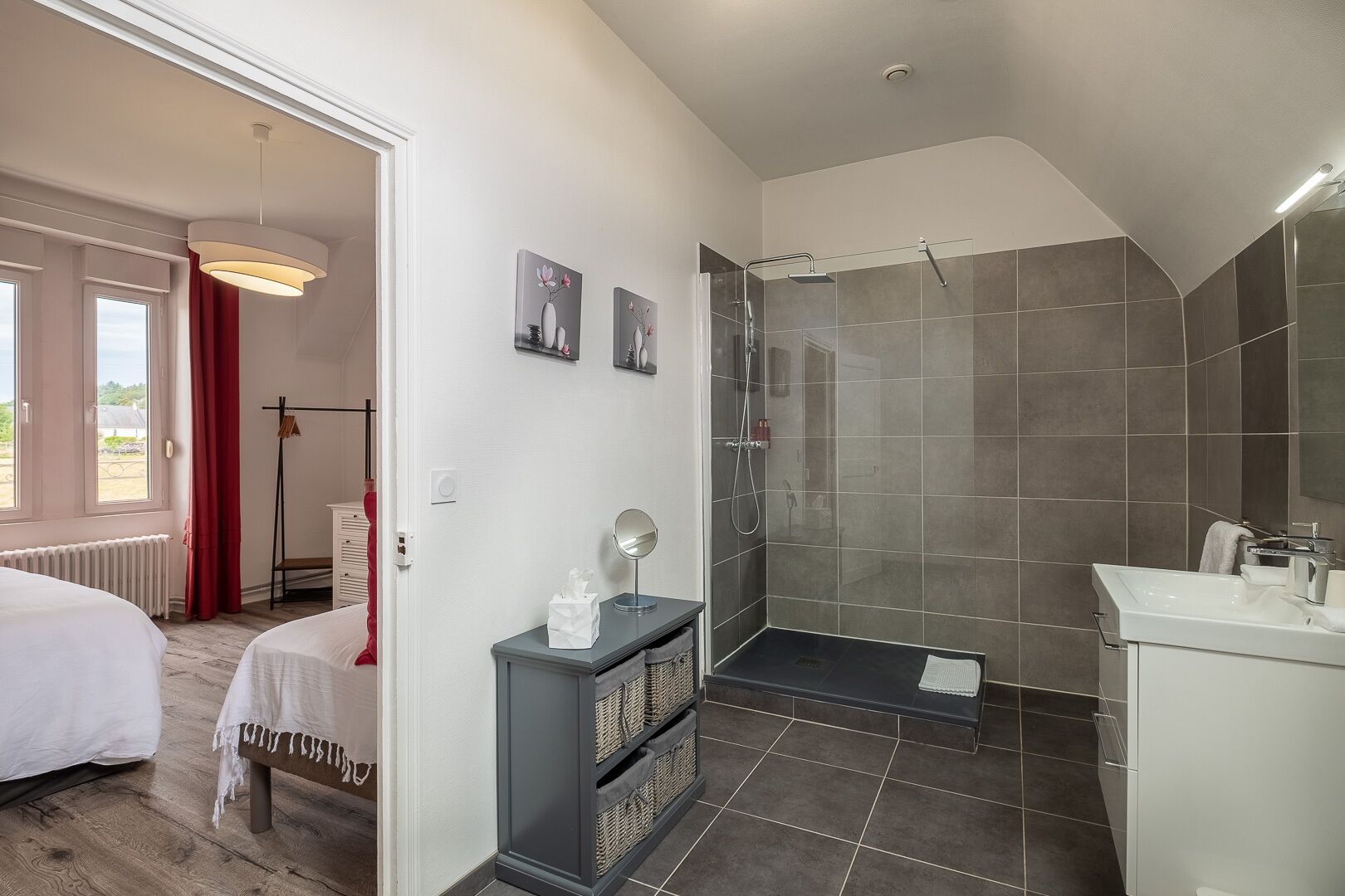A modern bathroom with a shower, a vanity, and a bedside table.
