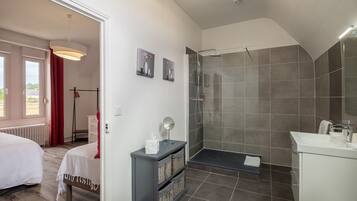 A modern bathroom with a shower, a vanity, and a bedside table.