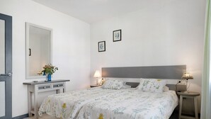 Une chambre à coucher comprenant un lit, des tables de chevet, une commode, un miroir et deux tableaux encadrés accrochés au mur.
