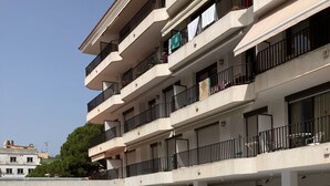 A swimming pool with lounge chairs, a clear sky, and a multi-story building with balconies. - Sunny 2-Bedroom Apartment with Terrace - shared Pool, Parking - Mountain View and close to the Beach (Tossa De Mar)