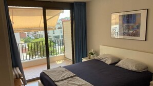 A bedroom with a bed, a nightstand, a framed picture, and a view of the outside balcony. - Sunny 2-Bedroom Apartment with Terrace - shared Pool, Parking - Mountain View and close to the Beach (Tossa De Mar)