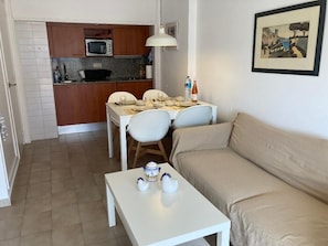 Un espacio habitable compacto con kitchenette, comedor y sofá.
