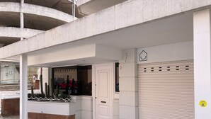 A building with a closed shutter, a door, and a window with a reflection of a car and cacti. - Sunny 2-Bedroom Apartment with Terrace - shared Pool, Parking - Mountain View and close to the Beach (Tossa De Mar)