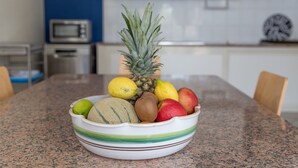 Un saladier rempli d’un assortiment de fruits est posé sur un plan de travail de cuisine.