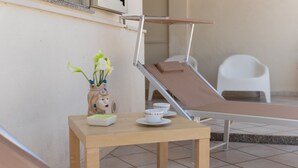 Une pièce baignée de lumière, avec une table en bois, un fauteuil inclinable et une petite chaise blanche.