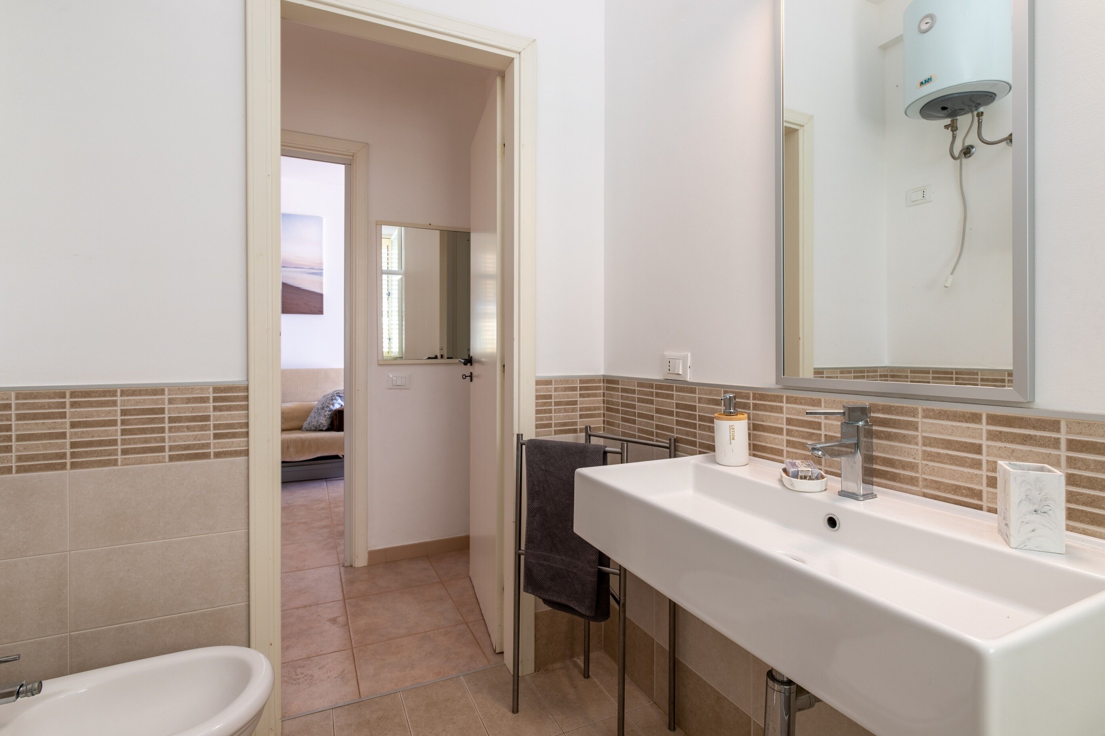 Een badkamer met een wastafel, spiegel, handdoekrek en douche.
