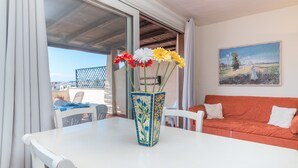Une table blanche avec un vase de fleurs, un canapé rouge et un tableau accroché au mur.