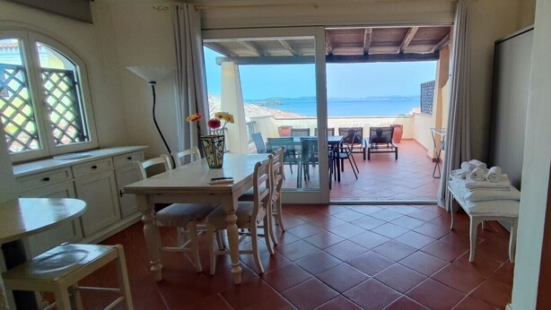 Une pièce comprenant un coin repas, une cuisine et offrant une vue sur la mer.