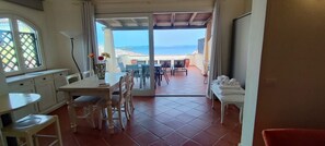Une pièce comprenant un coin repas, une cuisine et offrant une vue sur la mer.