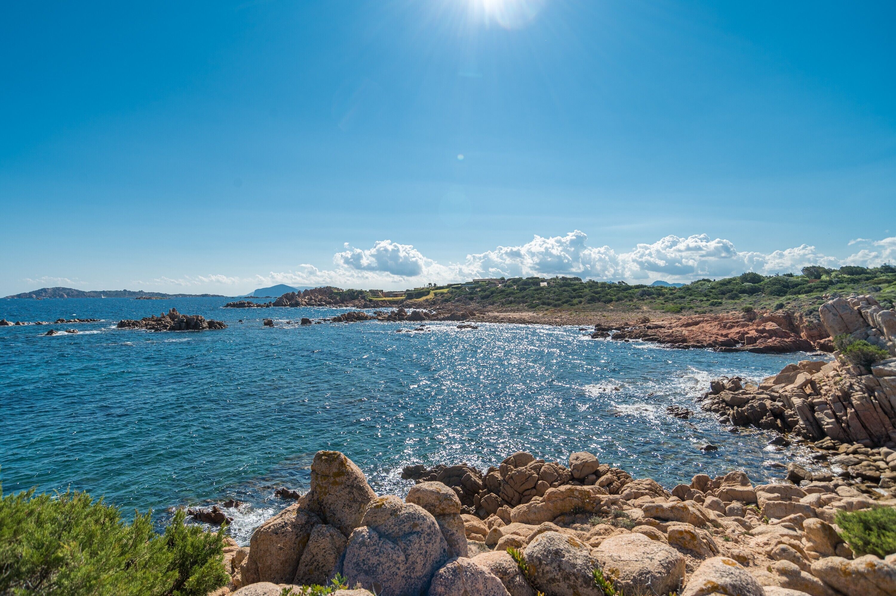A coastal landscape with rocky terrain and a clear blue sky.