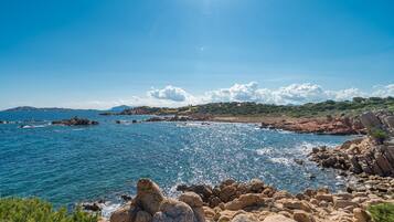 A coastal landscape with rocky terrain and a clear blue sky.