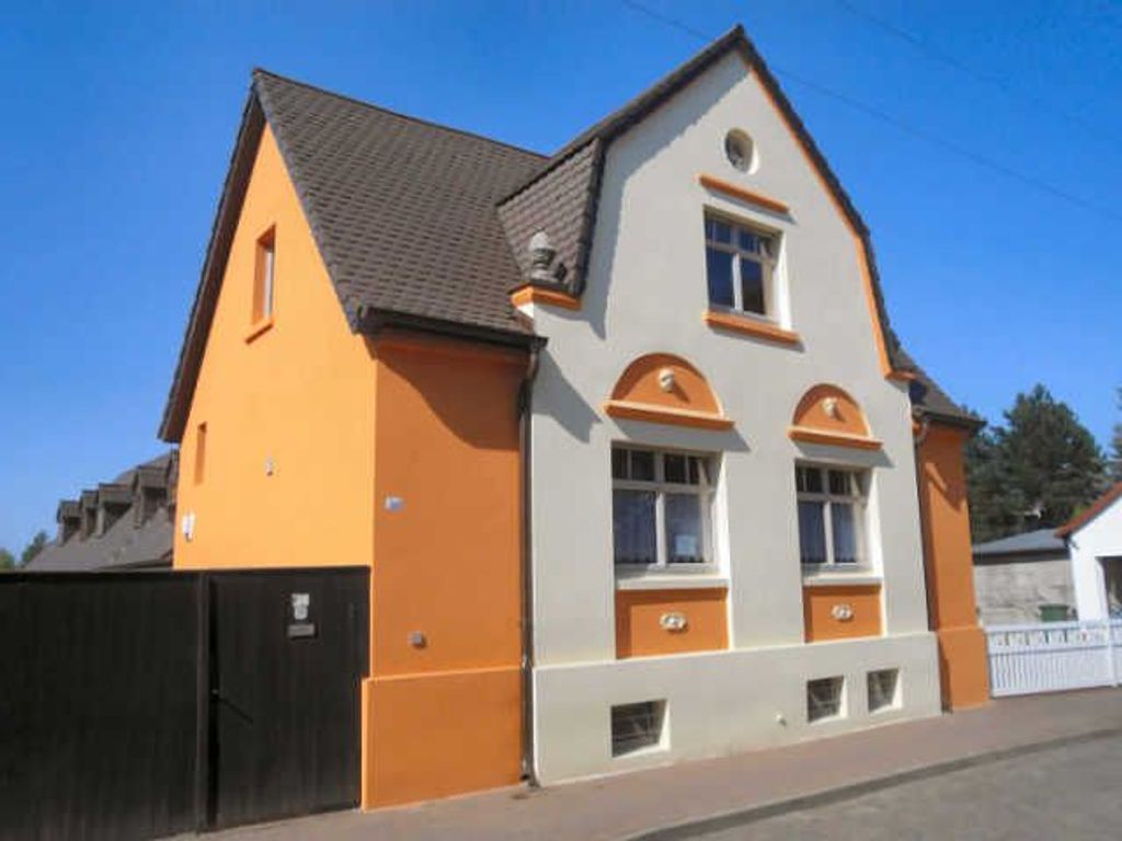 Ein zweistöckiges Gebäude mit Satteldach, einem kleinen Fenster im Obergeschoss und einer Tür im Erdgeschoss.