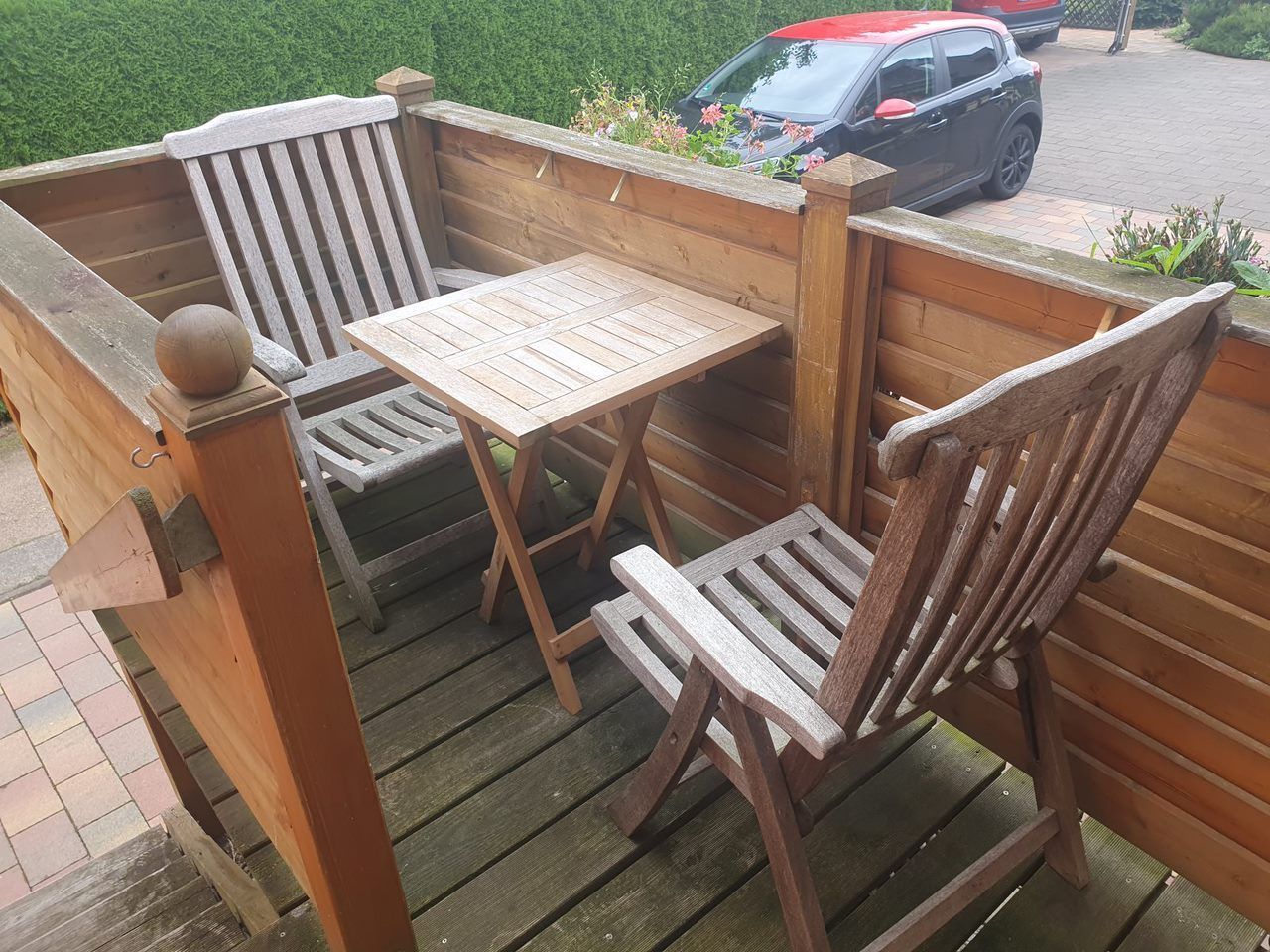 Eine Holzterrasse mit zwei Stühlen und einem Tisch.