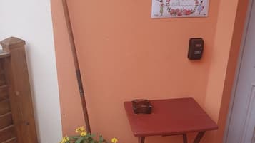 A small outdoor area with a wooden table, a hanging welcome sign, and a mailbox.