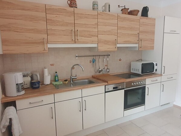 A kitchen with wooden cabinets, a microwave, a sink, and a stove.