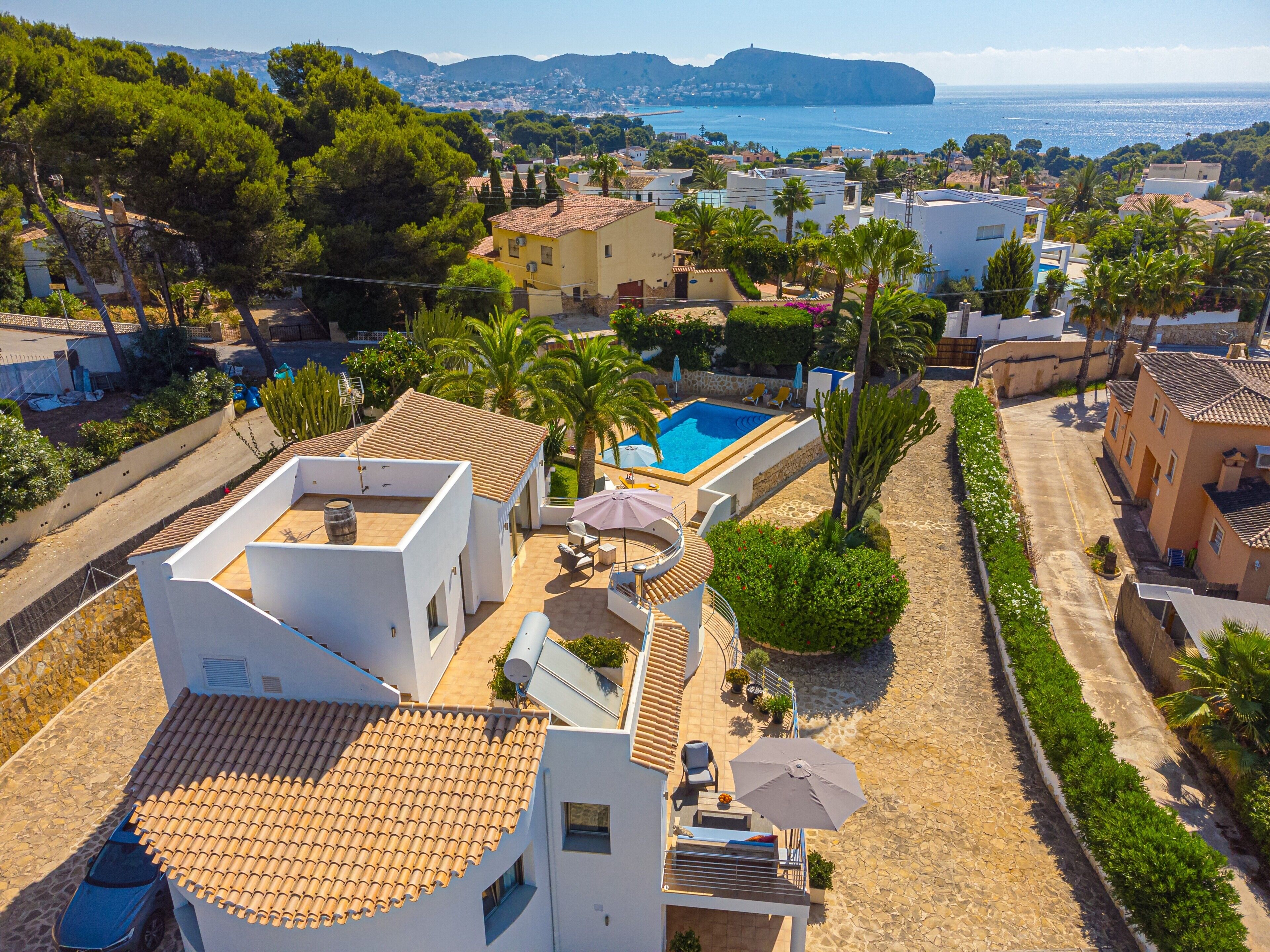 A residential area with a swimming pool, a patio with outdoor furniture, and a view of the sea.