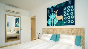 Un dormitori amb un llit gran, un mirall, una obra d'art a la paret i una porta que dona a una altra habitació.