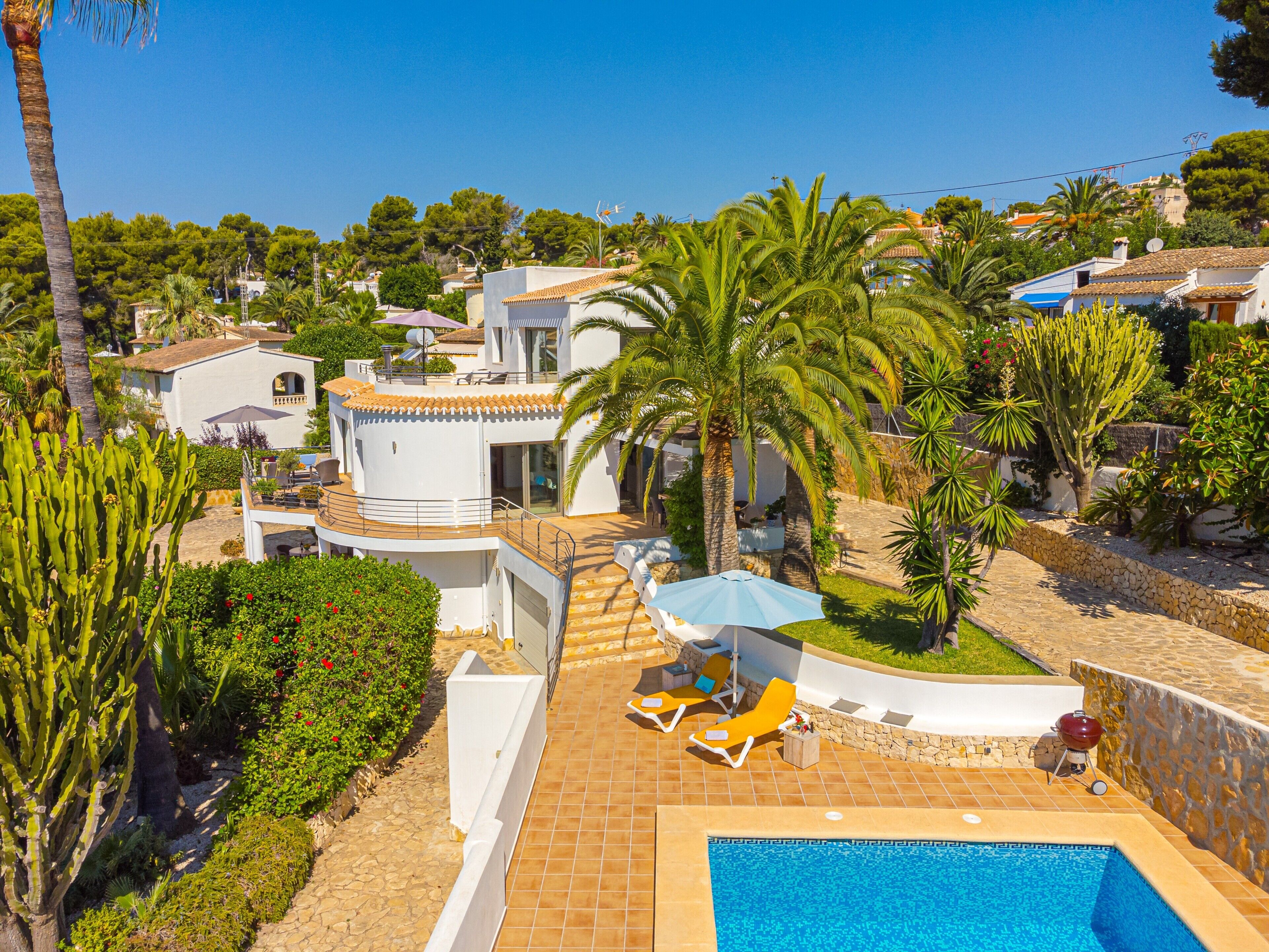 A poolside area with a pool, lounge chairs, and a barbecue grill.