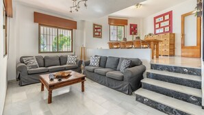 Ein geräumiger Wohnbereich mit zwei grauen Sofas, einem Holztisch und einer Treppe zu einer Holztür.