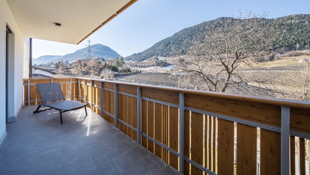 A balcony with a view of mountains and a chair. - Apartment "Sunnig - Sonnenaufgang" with Mountain View, Balcony & Wi-Fi (Völlan)
