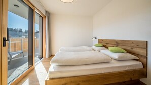 A bedroom with a wooden bed, a large window, and a view of the outdoors. - Apartment "Sunnig - Sonnenaufgang" with Mountain View, Balcony & Wi-Fi (Völlan)