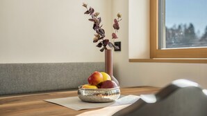 A wooden table with a glass bowl of fruit and a vase with dried flowers. - Apartment "Sunnig - Sonnenaufgang" with Mountain View, Balcony & Wi-Fi (Völlan)